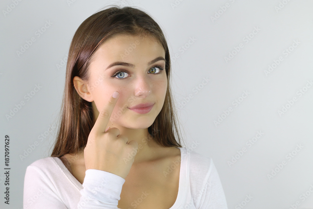 Belle jeune femme appliquant une crème hydratante sur son visage Belle jeune femme appliquant une crème hydratante sur son visage