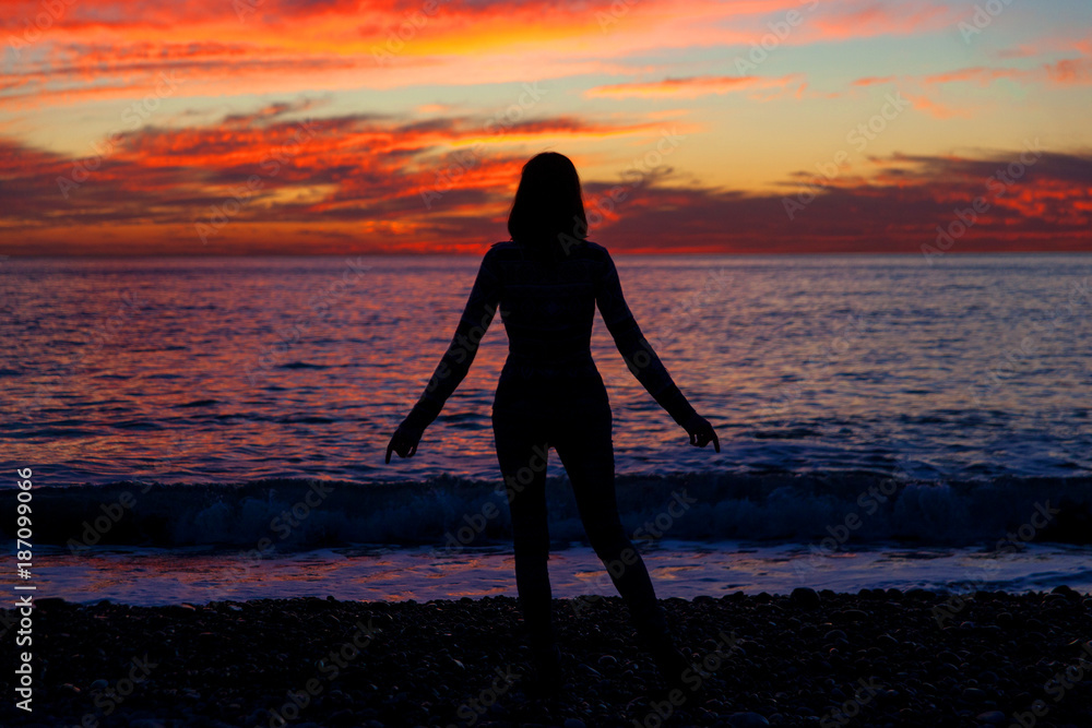 Woman silhouette on sea sunset. Travelling alone. Meditative nature and human concept.