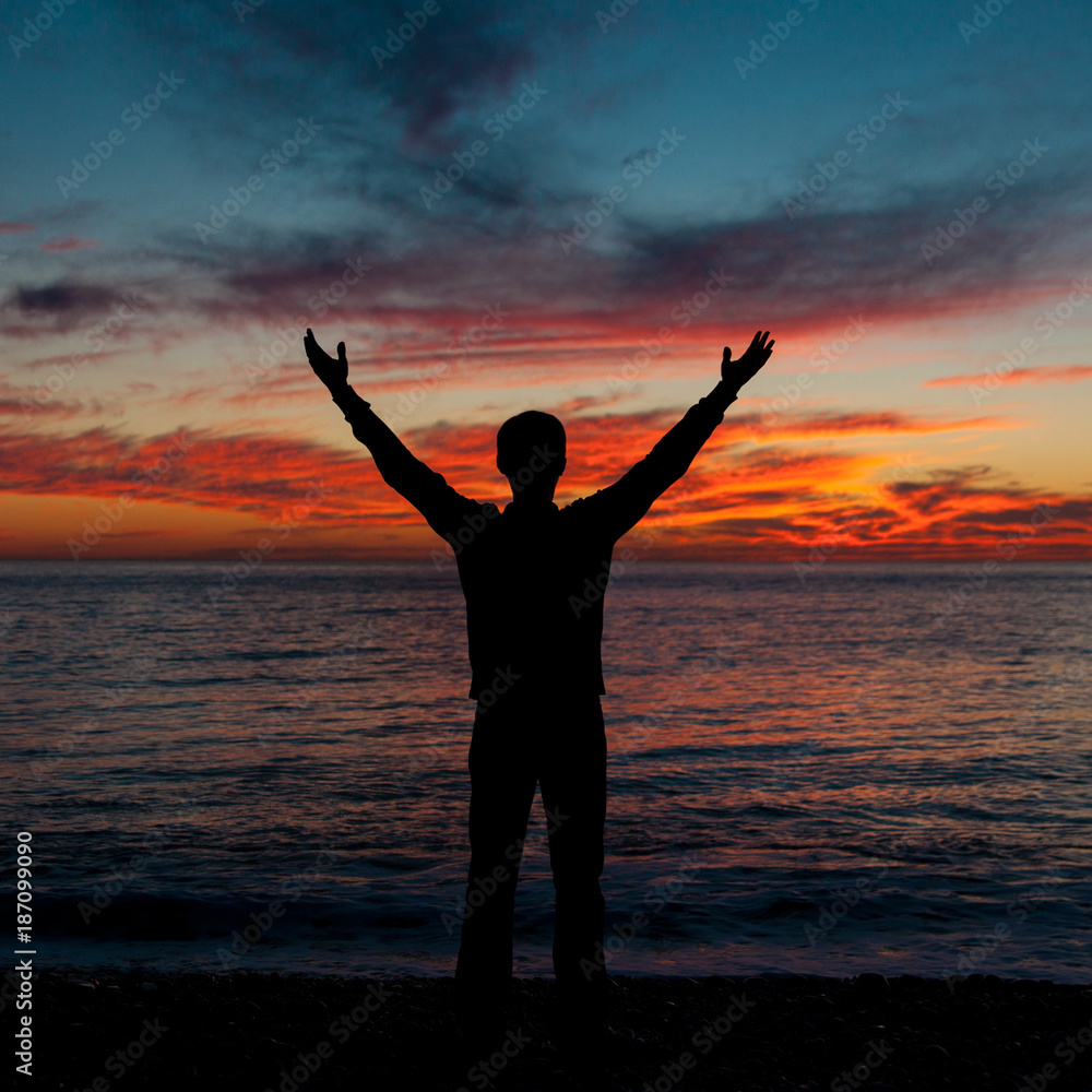 Man with arms up wide open silhouette on sea sunset. Travelling alone. Meditative nature and human concept. Man with arms up wide open silhouette on sea sunset. Travelling alone. Meditative nature and human concept.