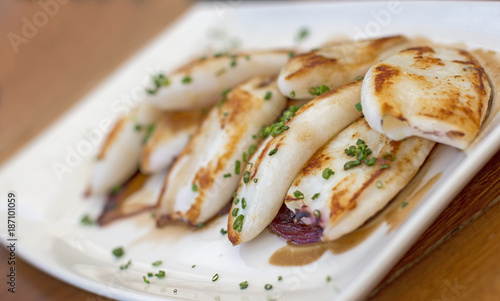 Grilled squid on a bed of caramelized red onions and decoration with chives.