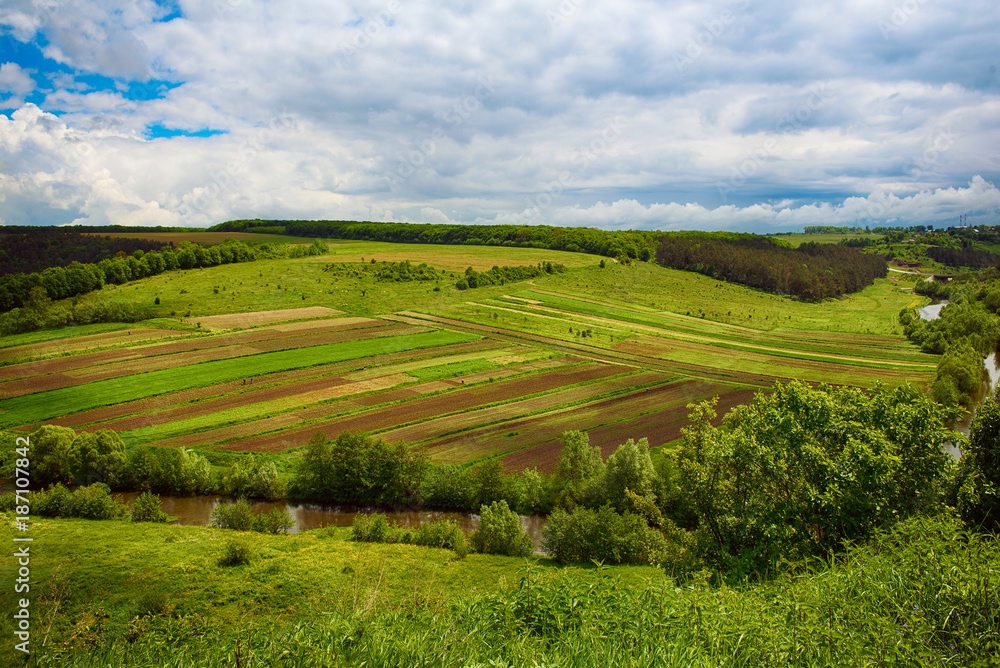 Rural landscape with fields, waves and blue sky with clouds, spring seasonal natural background