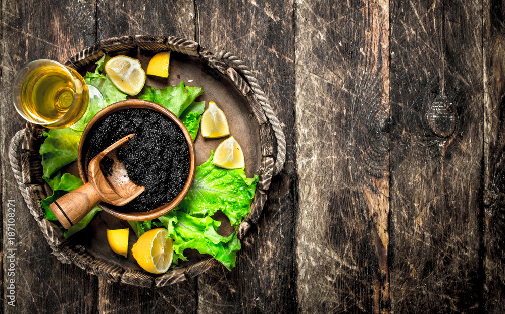 Black caviar with a glass of wine and greens.