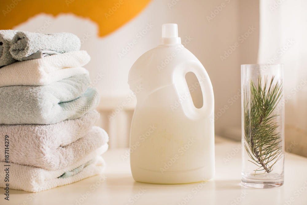 An abstergent, folded towels and vase on a table in the room An abstergent, folded towels and vase on a table in the room