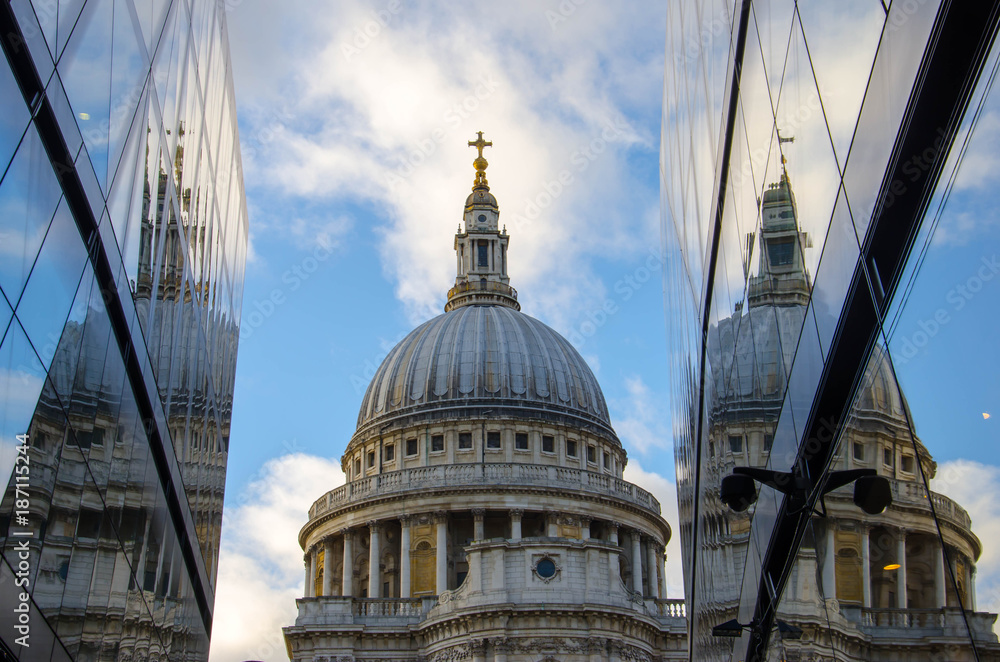 The dome of St Paul's Cathedral in London reflected in windows with blue sky and clouds