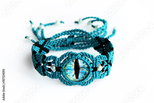 turquoise bracelet for the hand from waxed thread, and dragon eye in the technique of macrame on a white background