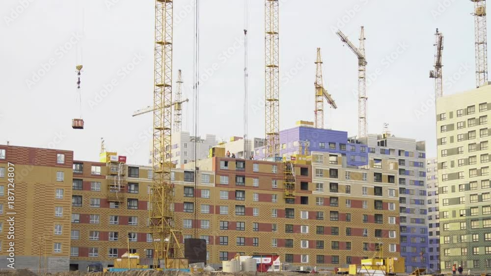 Builder works at against background of the construction site high-rise buildings. Builder works at against background of the construction site high-rise buildings.