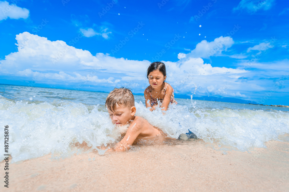 Cute boy and girl having fun on the sunny tropical beach. Lying on sand, wonderful waves around them. View from above. Vibrant color concept, copy space Cute boy and girl having fun on the sunny tropical beach. Lying on sand, wonderful waves around them. View from above. Vibrant color concept, copy space