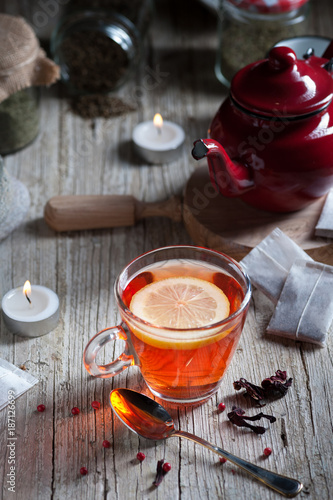 Glass with red tea on rustic wooden table.