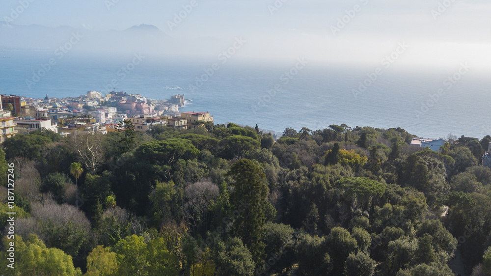 aerial view of the Villa Floridiana in the Vomero district in Naples, Italy. In the park there are many trees and plants. In the background the sea of the Gulf of Naples.
