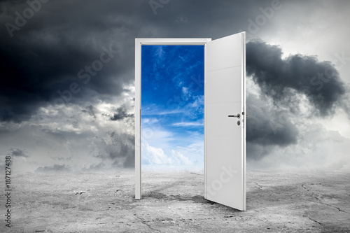 white open door with blue sky on concrete floor in front of dark cloudy background / business chance motivation concept / tür offen konzept  photo