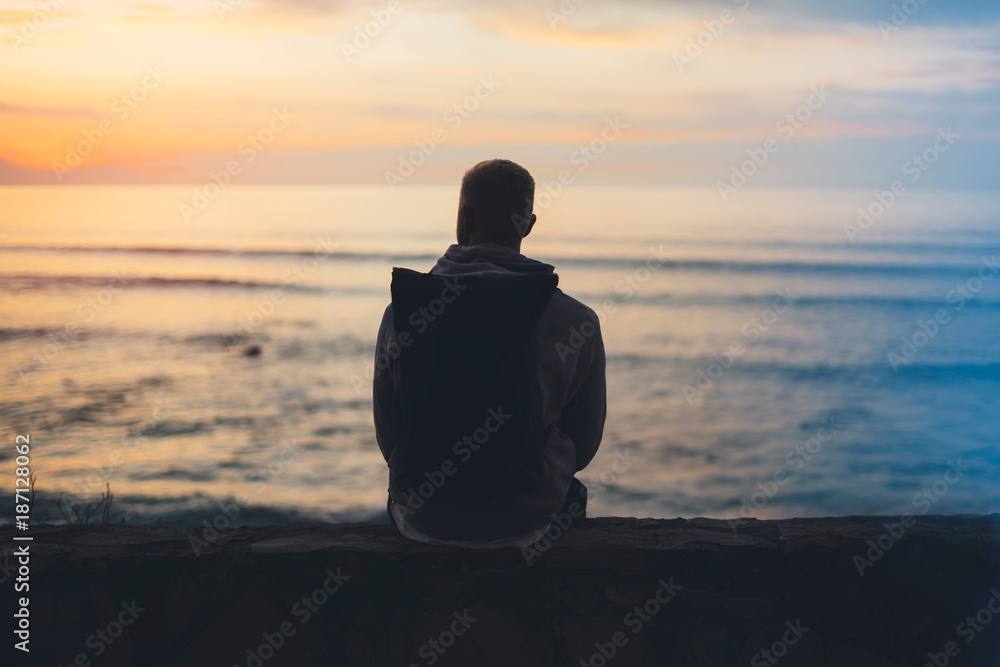 Hipster hiker tourist with backpack looking seascape sunset on background blue sea, guy enjoying ocean horizon, panoramic sunrise, traveler relax holiday concept, sunlight view in trip vacation
