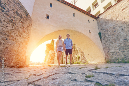 Junges Touristenpaar spaziert durch Torbogen am Innufer in Passau