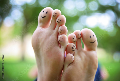 smiley faces on a pair of feet on all ten toes in a park on a hot summer day photo