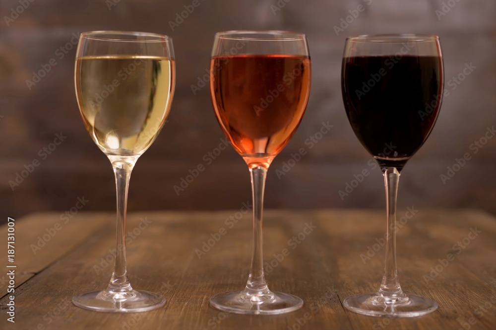 Three different glasses of wine on a wooden surface