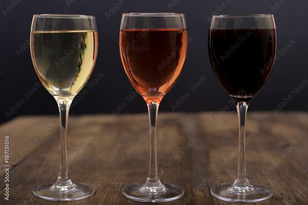 Three different glasses of wine on a wooden surface