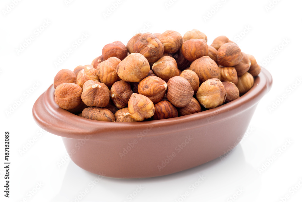 hazelnuts in clay bowl on white background hazelnuts in clay bowl on white background