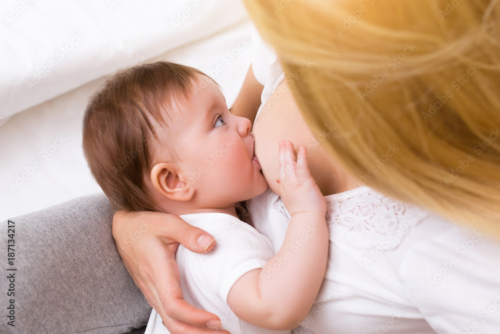 Mother breast feeding and hugging her baby.Young mother feeding breast her babyboy at home in white room. Mom breastfeeding her child whith breast milk Mother breast feeding and hugging her baby.Young mother feeding breast her babyboy at home in white room. Mom breastfeeding her child whith breast milk