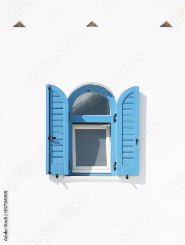 Window with blue shutters on a white wall