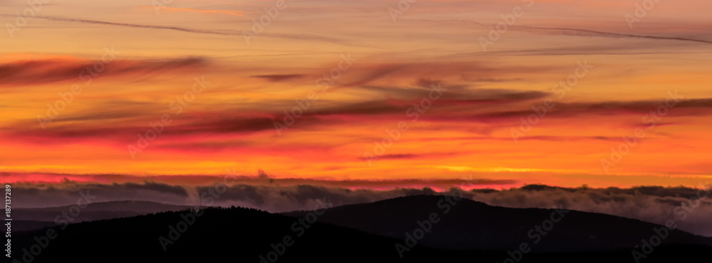 Obraz premium Fire in the sky. A strong play of colors with a strong red glow in the sky over the mountains. Chemtrails created this spectacle. Concept: weather or sunset / sunrise