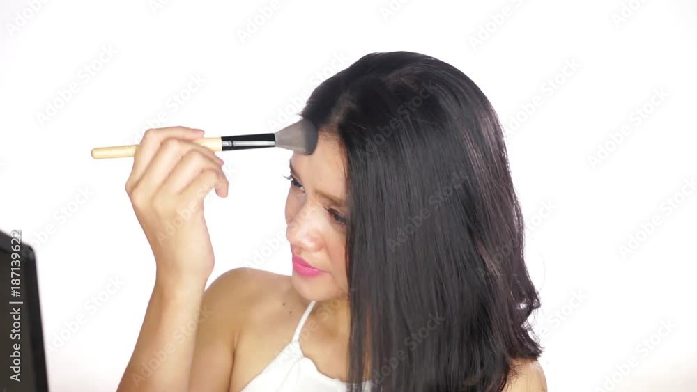 Beautiful young woman applying makeup with a brush on her cheek, isolated on white background Beautiful young woman applying makeup with a brush on her cheek, isolated on white background