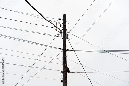 Chaos of cables and wires on electric pole, Messy wires attached to electrics pole in Bangkok, Thailand on blue sky background. photo