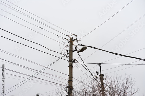 Chaos of cables and wires on electric pole, Messy wires attached to electrics pole in Bangkok, Thailand on blue sky background.