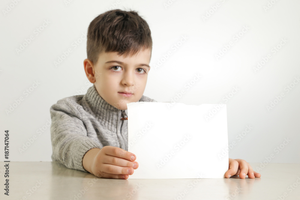Studio portrait of young boy holding white blank paper Studio portrait of young boy holding white blank paper