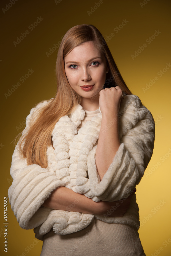 Beauty portrait of woman in fur winter jacket over yellow background Beauty portrait of woman in fur winter jacket over yellow background