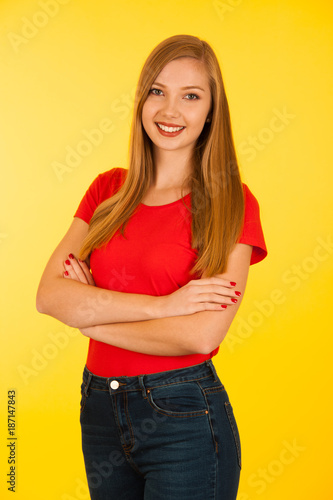 Beautiful young woma in red t shirt and jeans over yellow background