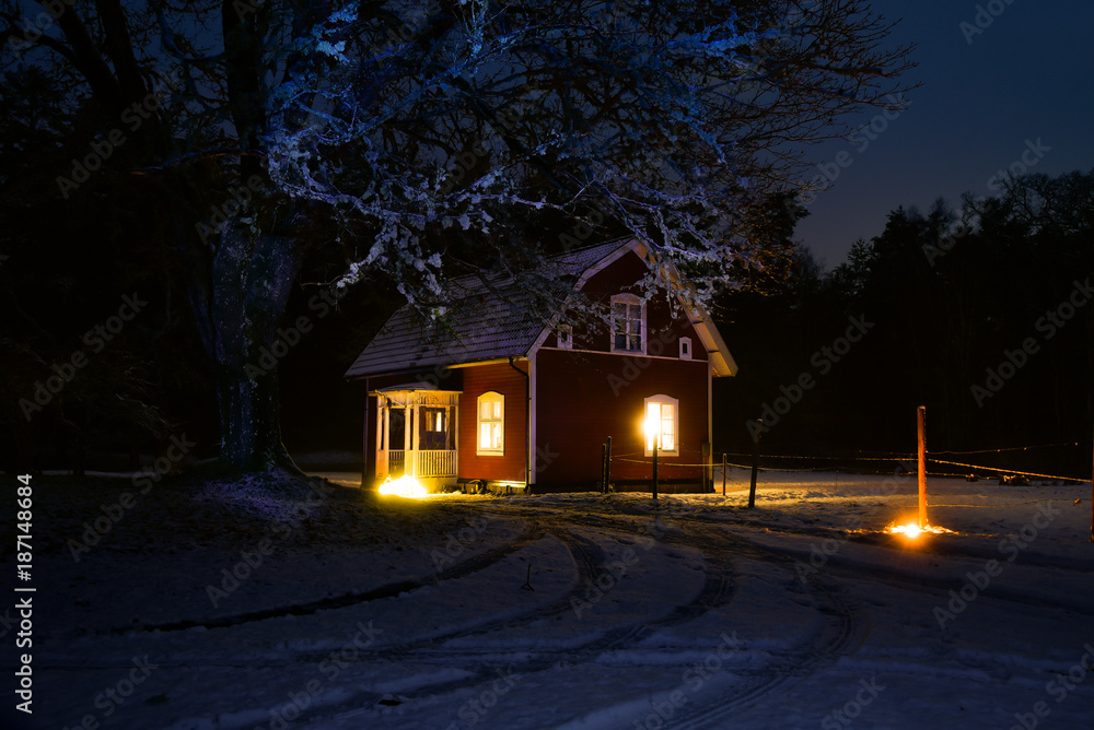 Fototapeta premium Old red wooden house in wintry Sweden in the evening