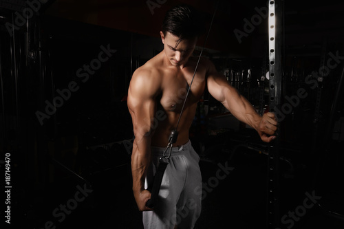 Young man training on exercise machine in gym