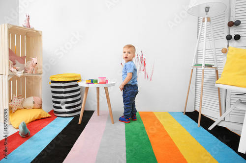 Little boy painting on wall...