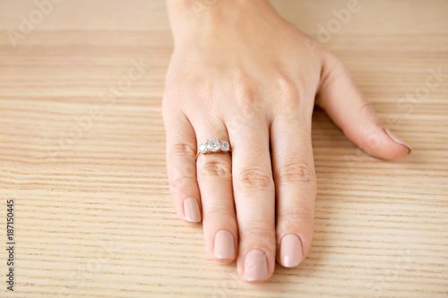 Woman's hand with beautiful engagement ring on table