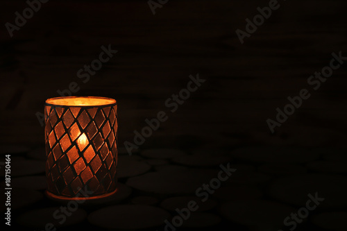 Holder with burning candle on dark background