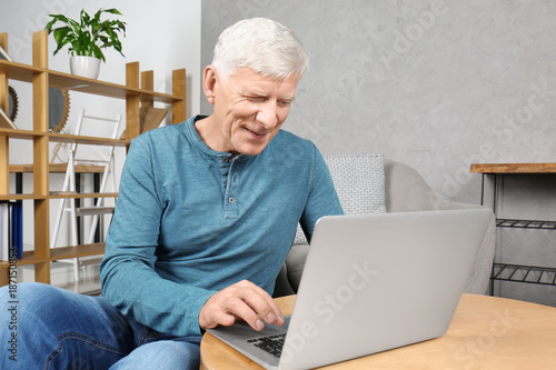 Attractive mature man with laptop indoors