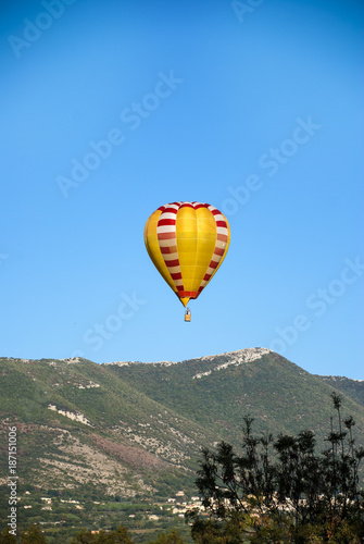 A hot air balloon, in flight to the mountains