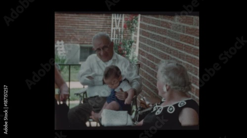 1960 Grandfather holds infant grandson on front porch