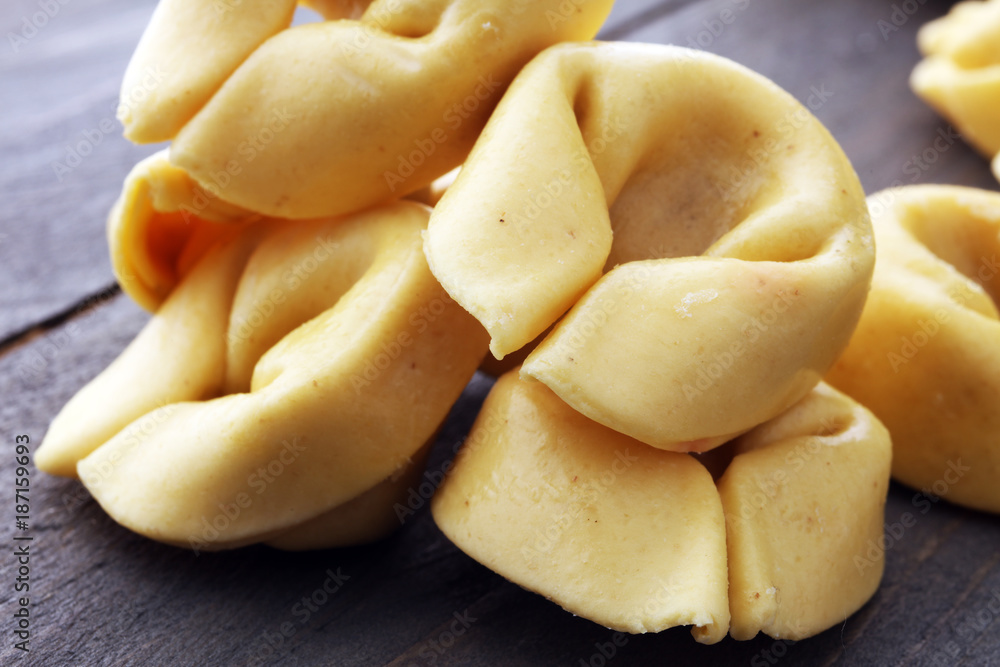 Raw cheese filled tortellini pasta on wooden background Raw cheese filled tortellini pasta on wooden background