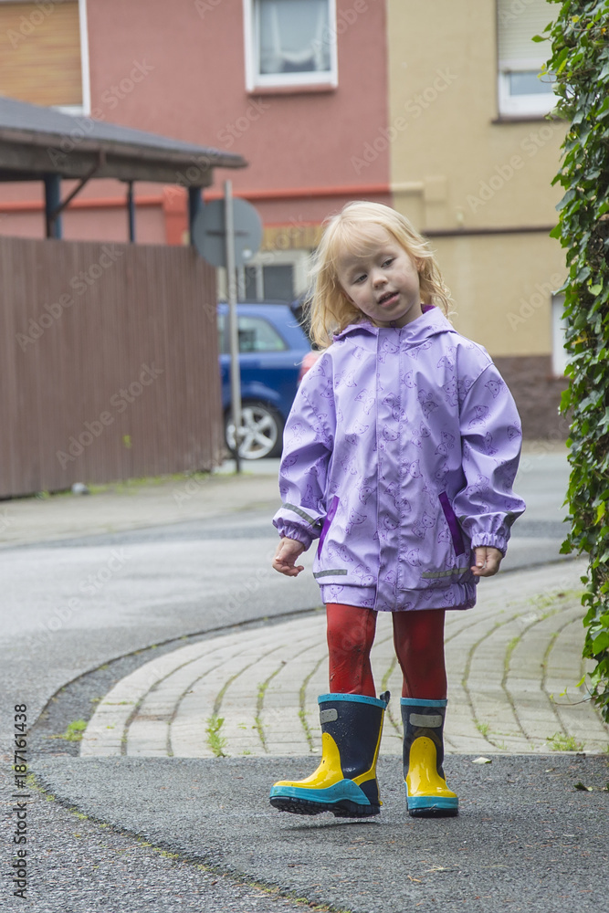 little girl in rubber boots. Wet, after street pranks.