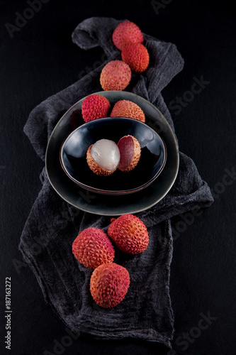 ripe, vermilion exotic lichees decorated on a slate plate kitchen table background with napkin