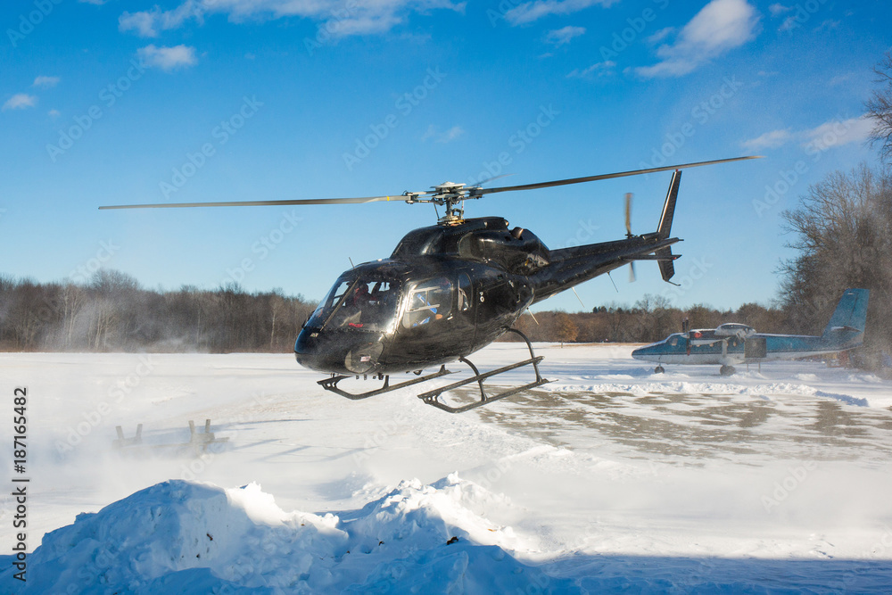 Naklejka premium solo black helicopter in blue skies with snow