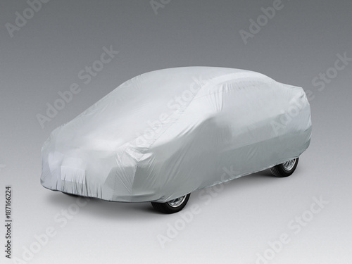 A car covered with a grey cloth, isolated on grey background.