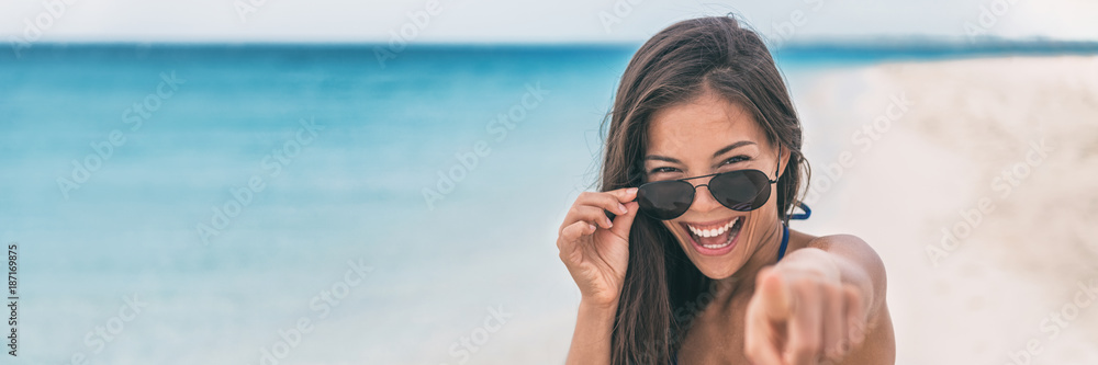 Happy young Asian woman excited pointing finger at camera. I choose you! concept people lifestyle on summer holiday. Panorama banner with copy space on blue ocean water background.