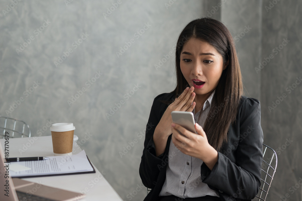 Excited asian business girl while reading a smart phone sitting in her workstation. Business Success Concept Excited asian business girl while reading a smart phone sitting in her workstation. Business Success Concept