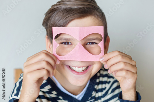 Valentine s Day. Mothers Day. Women s Day. Father s Day. A boy is holding a mask of heart-shaped hearts in his hands. Beautiful smile. Emotions