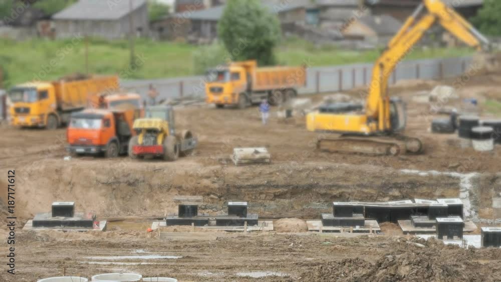 Large construction of large complex of buildings. Yellow excavator working on a construction site in the summer season Large construction of large complex of buildings. Yellow excavator working on a construction site in the summer season
