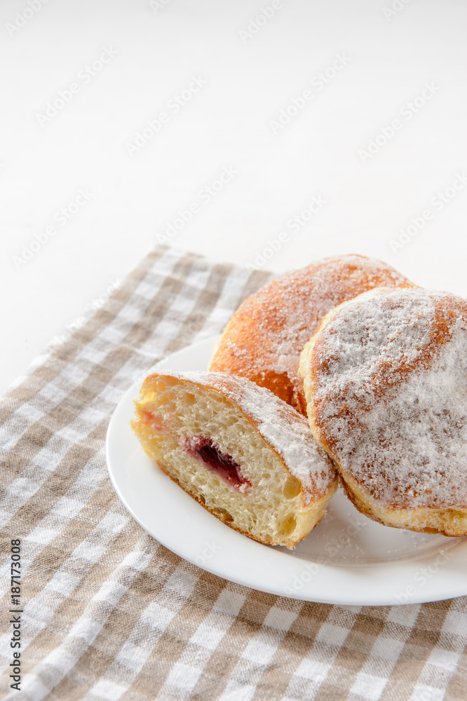 zweieinhalb 'Berliner' Pfannkuchen auf weißem Teller und Handtuch zweieinhalb 'Berliner' Pfannkuchen auf weißem Teller und Handtuch