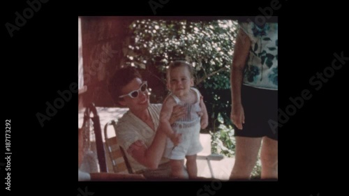 1960 mother and baby boy hanging out with family in backyard