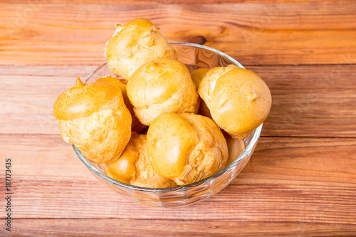 buns with cream in a glass vase on a wood table photo