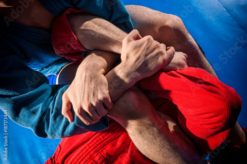 Photos Man wrestlers of grappling and jiu jitsu in a blue and red kimono makes submission wrestling